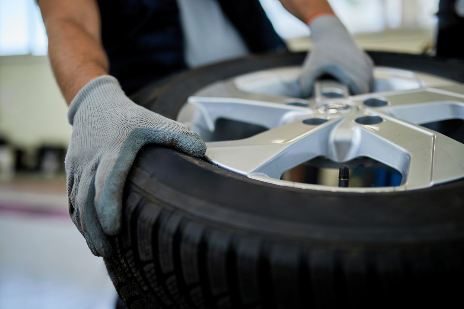 Close-up of auto repairman working on car tire in a workshop.